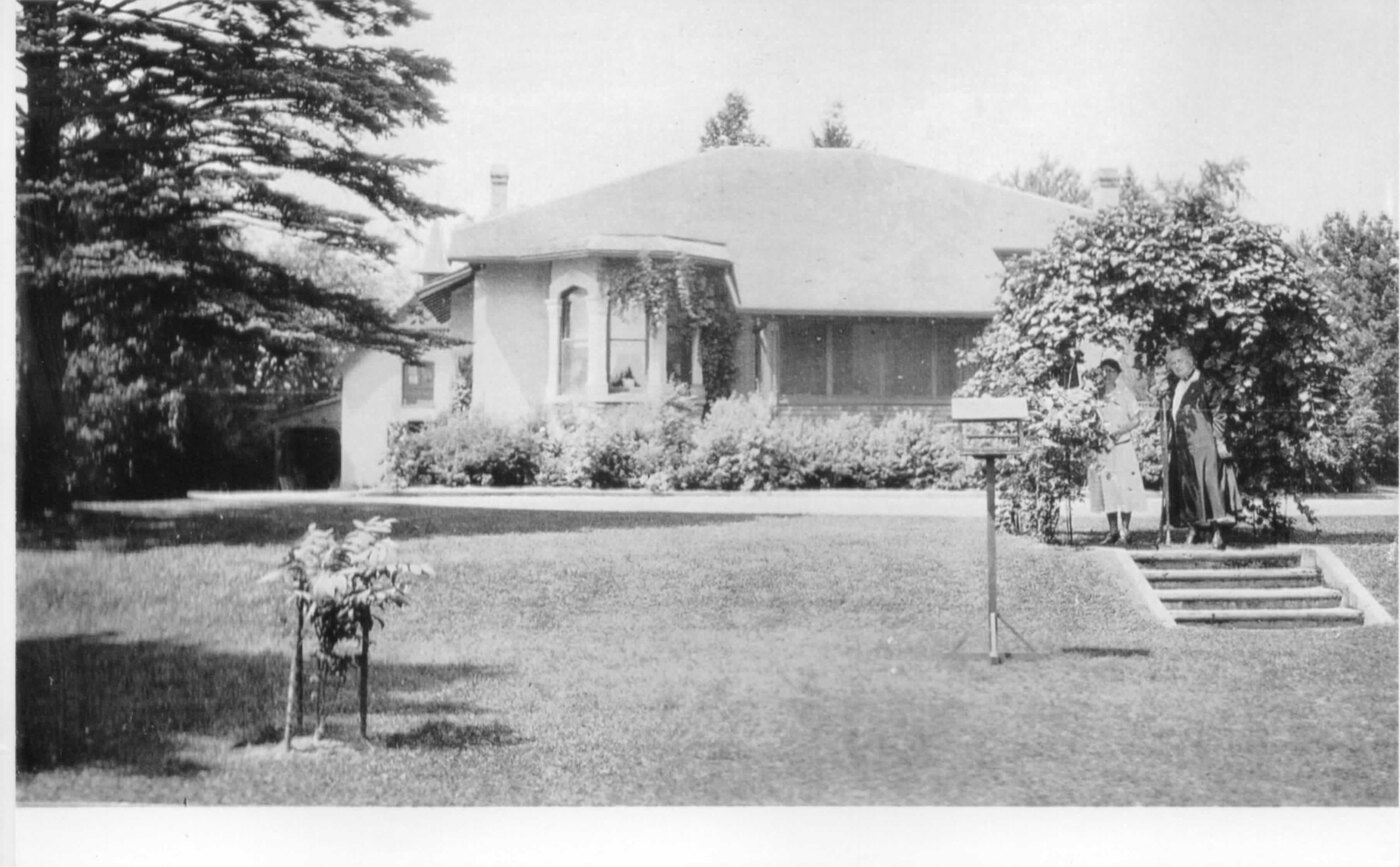 The reduced Gore bungalow seen from the lawn with two figures and a birdbath